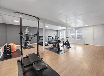 A gym with a variety of equipment including a leg press machine, exercise bikes, and a squat rack.